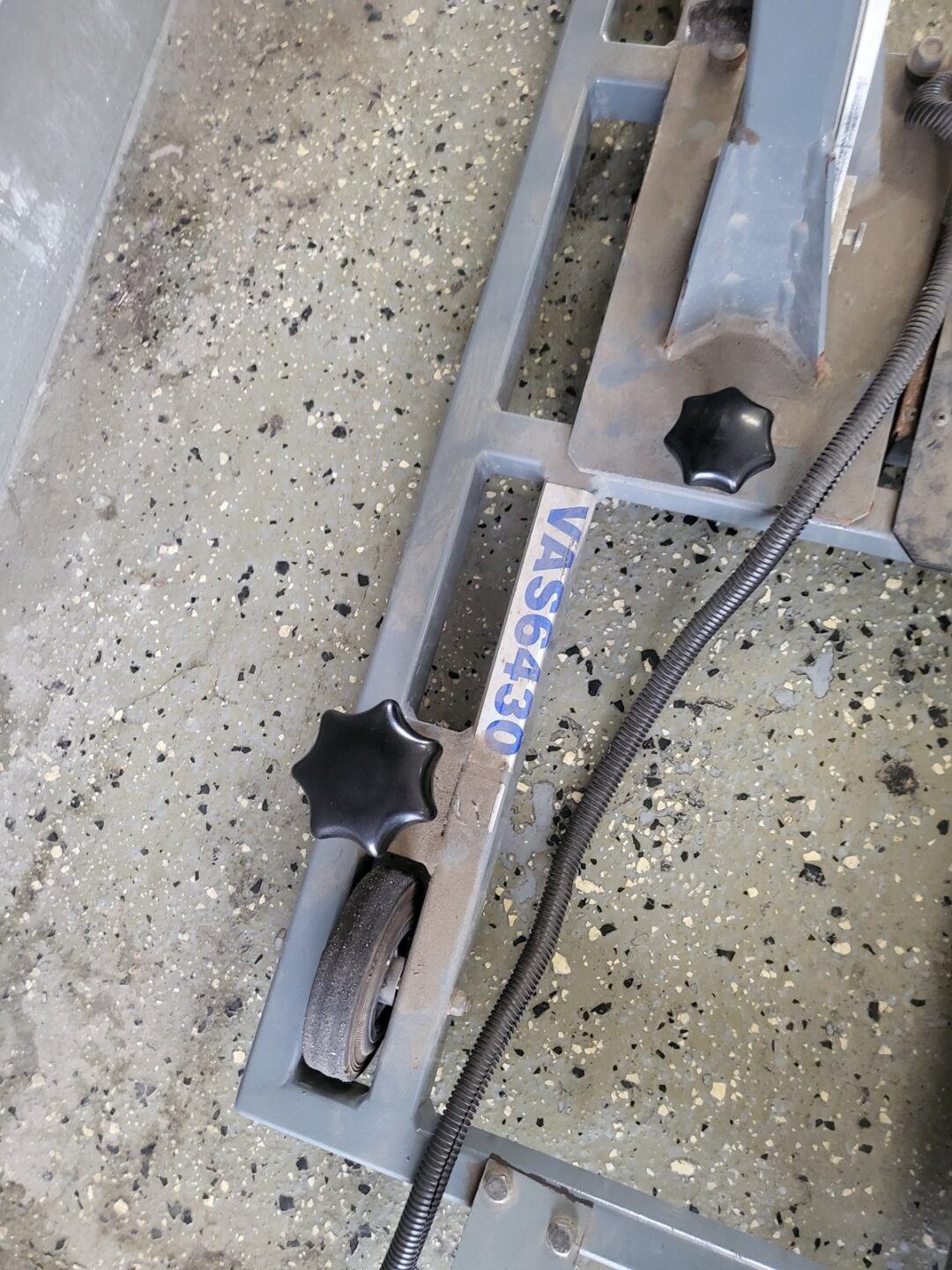 Close-up of VAS6430 alignment tool rail with star knobs and cable on shop floor