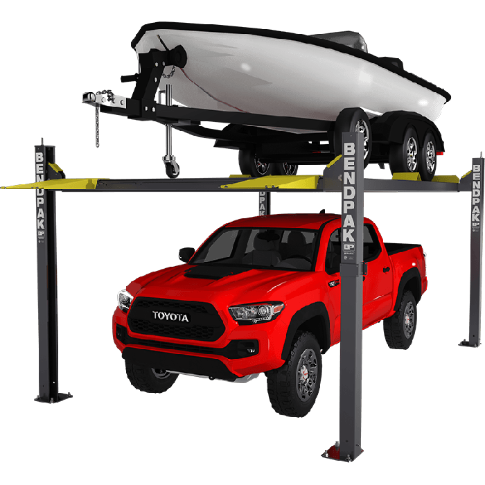 BendPak 4-post automotive lift holding boat on trailer above red Toyota Tacoma truck