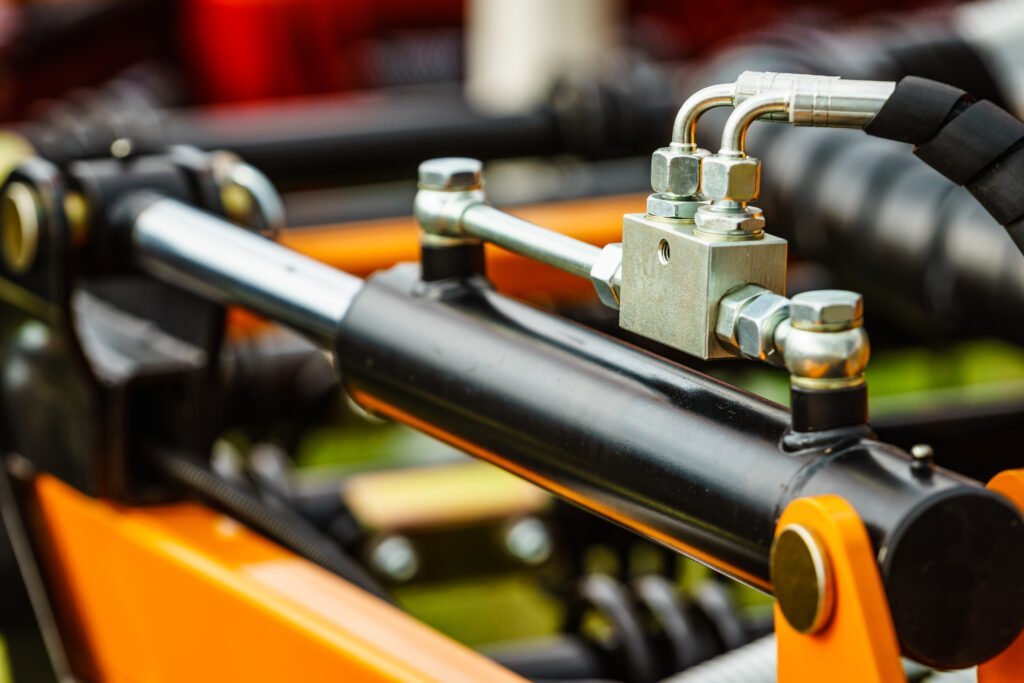 Close-up of hydraulic cylinder fittings and hoses on an automotive lift system
